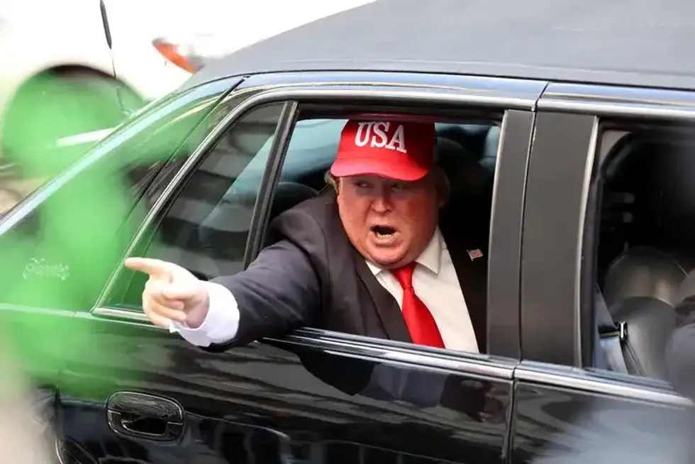 A person dressed as former President Donald Trump rides in a car past Trump Tower on April 04, 2023.