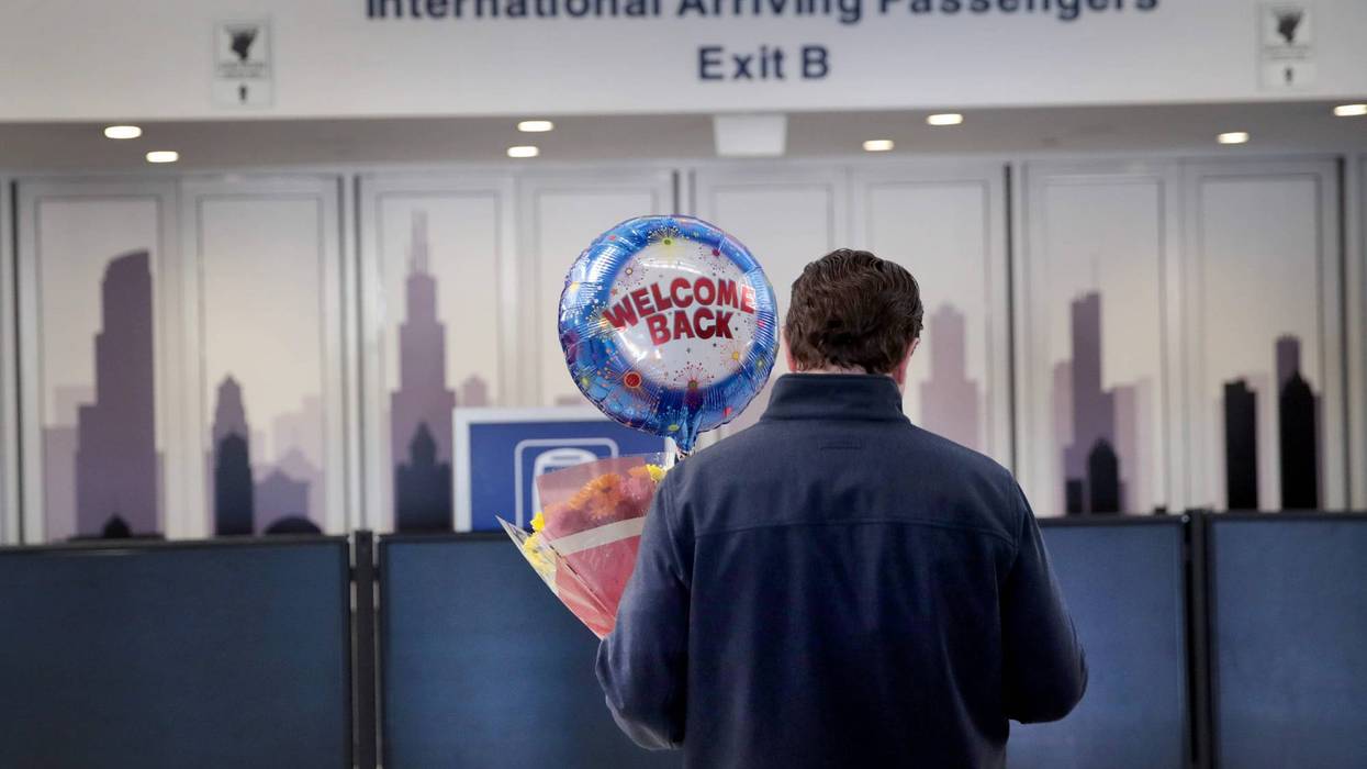 A person holds flowers and a balloon as they wait in O'Hare Airport's international terminal