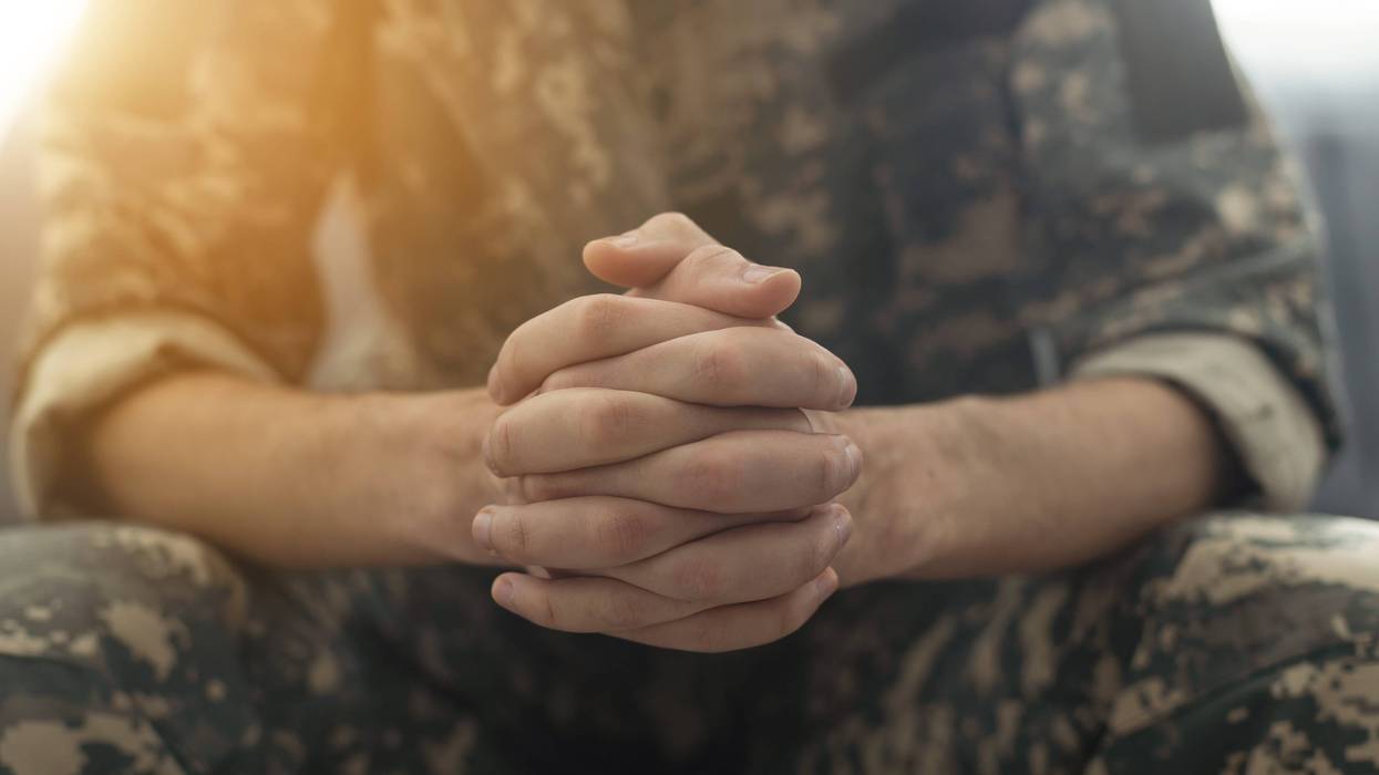 A person in a military uniform joining their hands together.