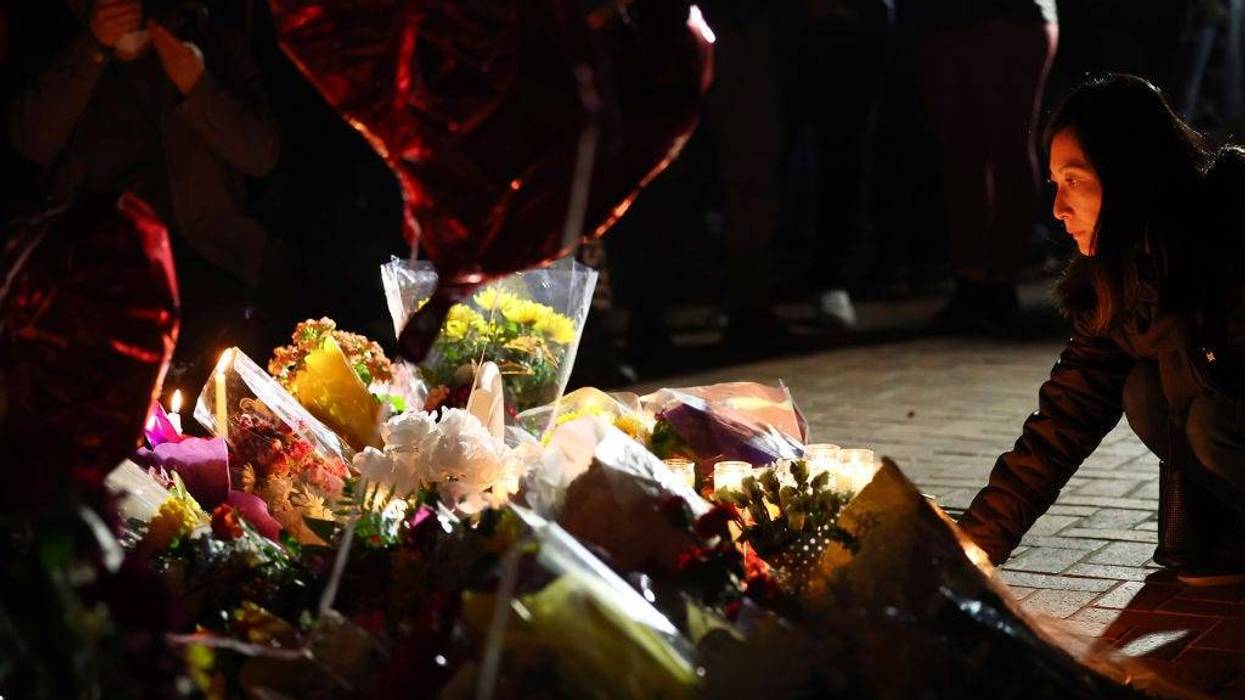 A person kneels at a candlelight vigil for victims of a deadly mass shooting at a ballroom dance studio on January 23, 2023 in Monterey Park, California.