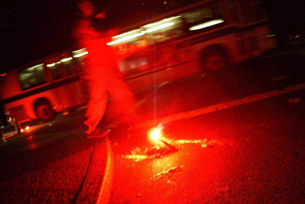 A person lights a fire on the curb in New York City.
