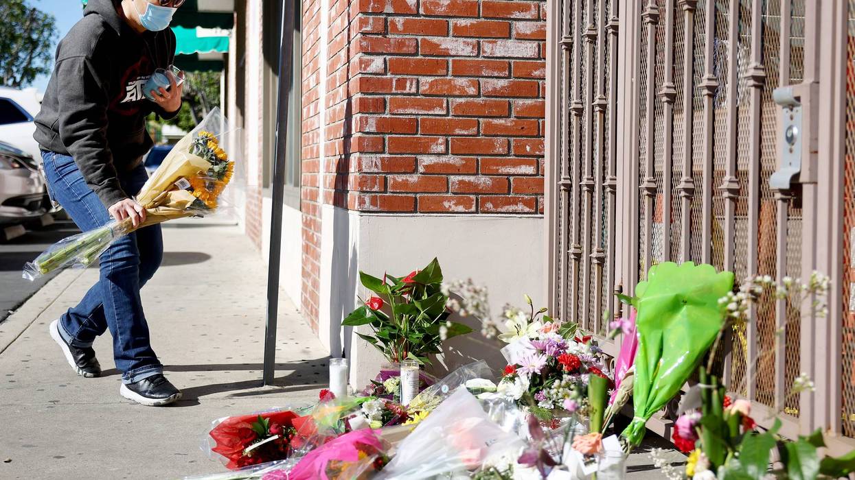 A person places flowers at a makeshift memorial outside the scene of a deadly mass shooting at a ballroom dance studio on January 23, 2023 in Monterey Park, California.