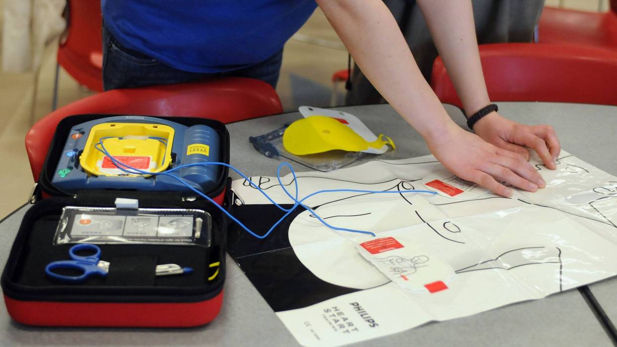 A person practices putting the patches of an AED onto a plastic cutout.
