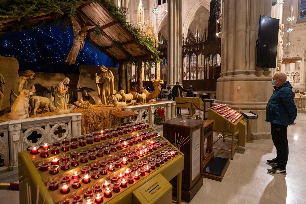 A person reflects at a diorama of the birth of Jesus Christ in St. Patrick