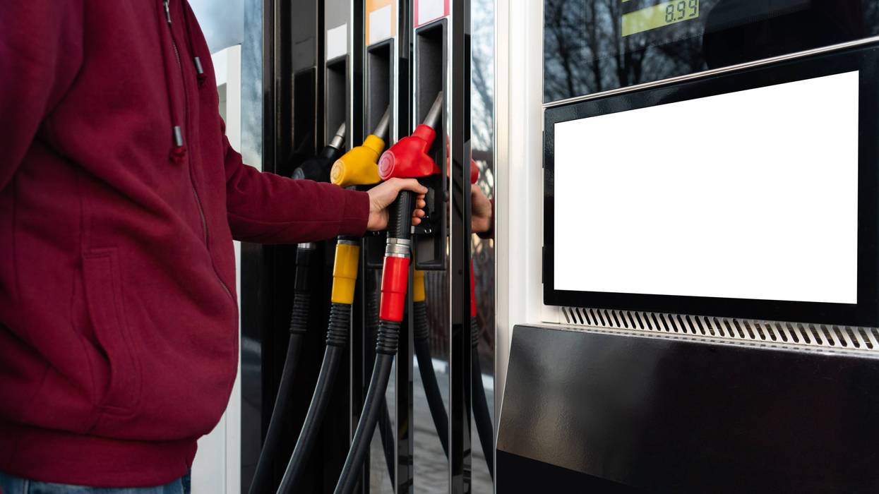 A person stands at a gas pump. Gas prices are at record highs, and some legislators are discussing a gas tax holiday.
