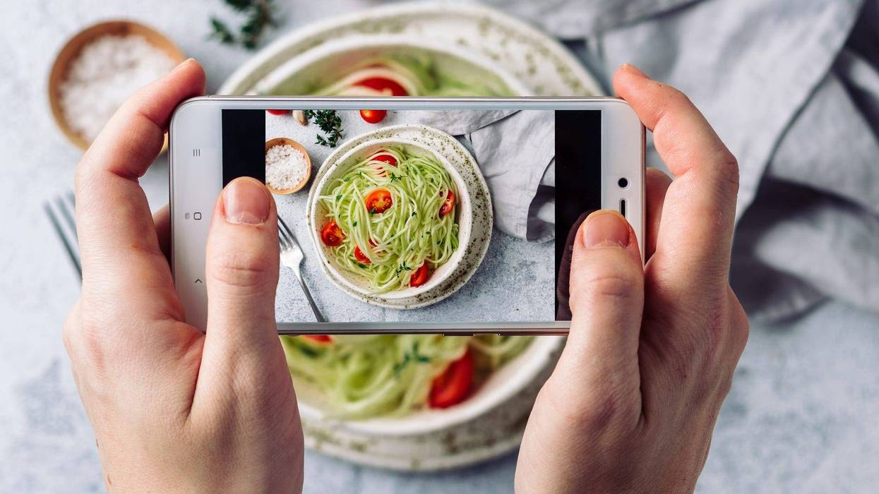 a person takes a photo with their phone of the food on a table
