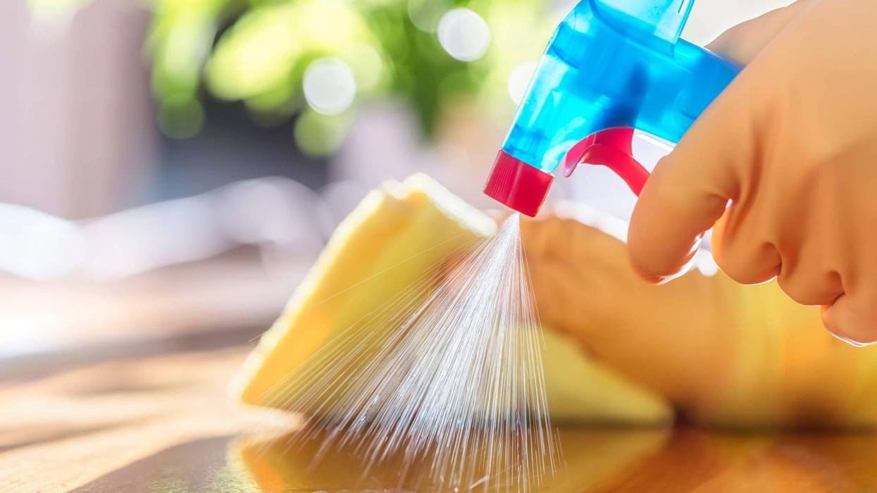 A person uses a spray bottle to clean a surface