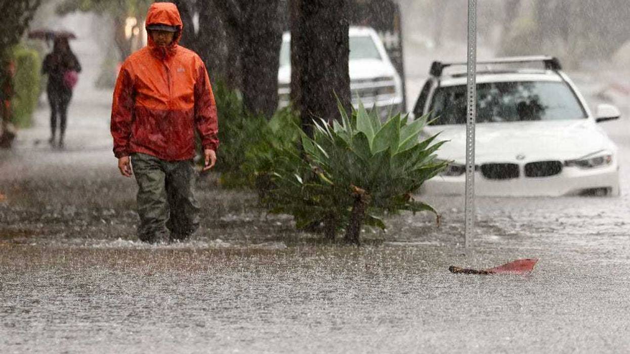 A person walks along a flooded street as a powerful long-duration atmospheric river storm, the second in less than a week, impacts California on February 4, 2024 in Santa Barbara, California. The storm is delivering potential for widespread flooding, landslides and power outages while dropping heavy rain and snow across the region.