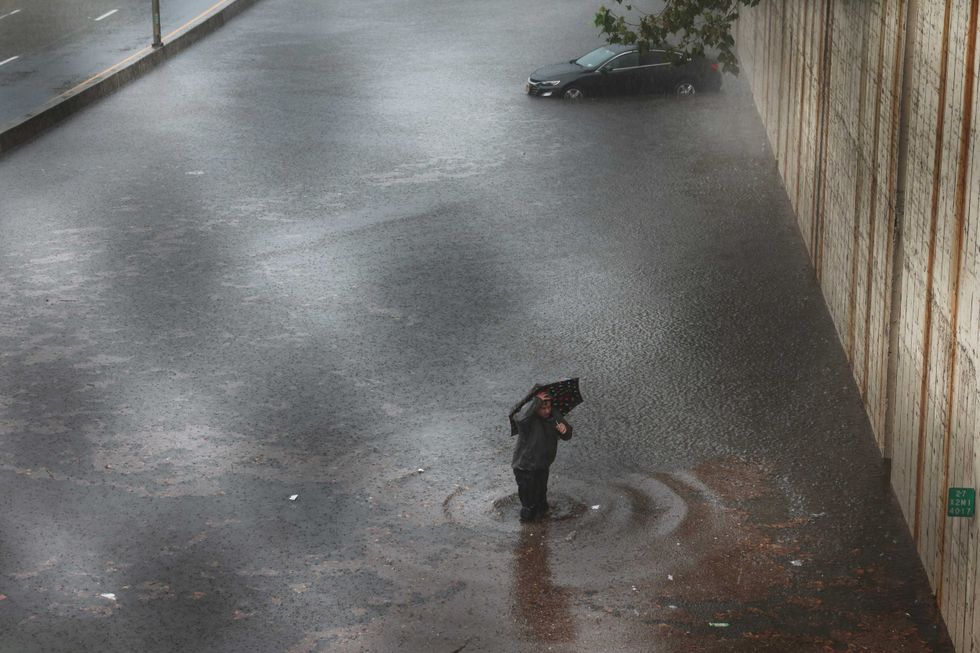 A person walks away from his vehicle after it got stuck in high water on the Prospect Expressway during heavy rain and flooding on September 29, 2023 in New York City.