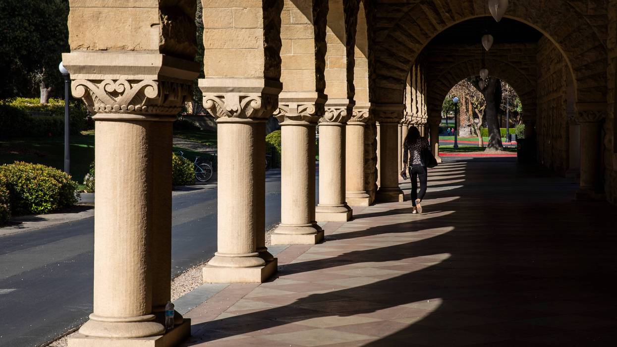 A person walks past archways during a quiet morning at Stanford University on March 9, 2020.