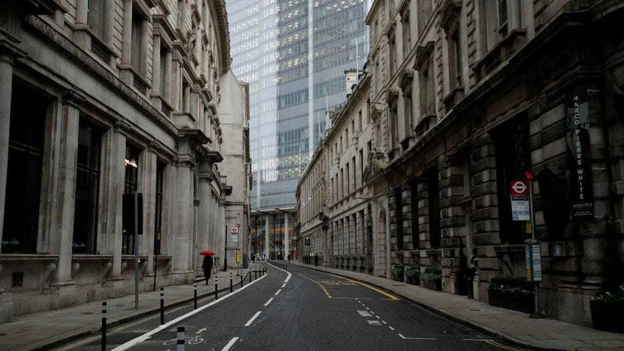 A person walks with an umbrella in light rain in the City of London financial district in London, Jan. 5, 2021, on the first morning of England entering a third national lockdown since the coronavirus outbreak began. (AP Photo/Matt Dunham)