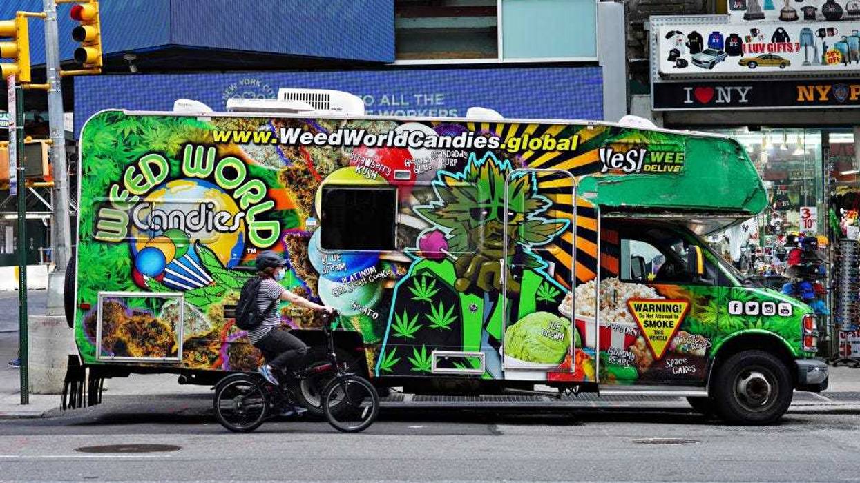 A person wearing a protective mask rides a bike by the Weed World Candies RV as the city continues Phase 4 of re-opening following restrictions imposed to slow the spread of coronavirus on August 21, 2020 in New York City.