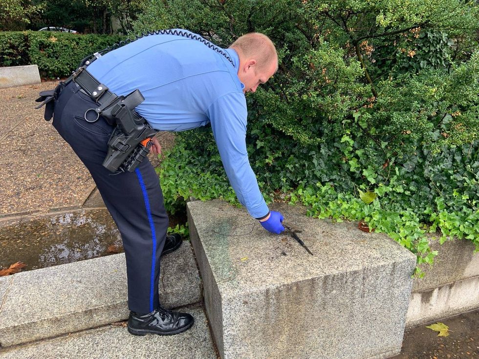 A Philadelphia police officer analyzing a gun-like object which Antonio Hernandez fished out of the Schuylkill River.