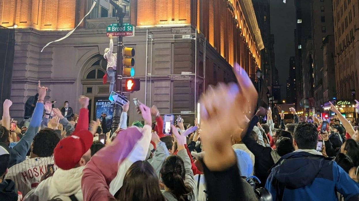 A Phillies fan defies Philadelphia police, gravity and slippery hydraulic fluid to climb a pole in celebration of the Phillies' NLCS victory on Sunday.