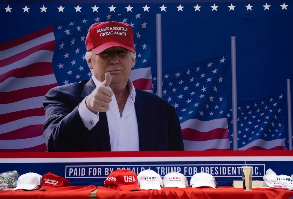 A photo of US President Donald Trump sits behind a table full of campaign hats as he speaks during a campaign rally at Florida State Fairgrounds Expo Hall in Tampa, Florida, on July 31, 2018.