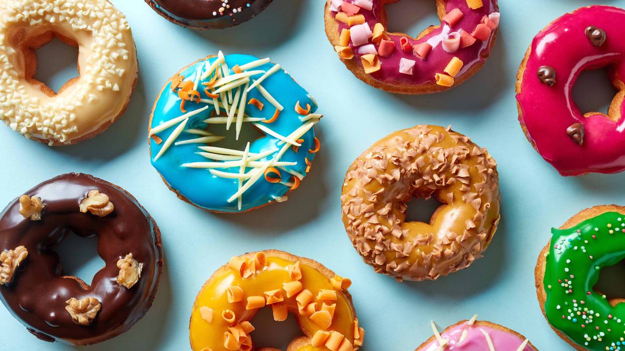 A plate with donuts in a variety of colors and flavors
