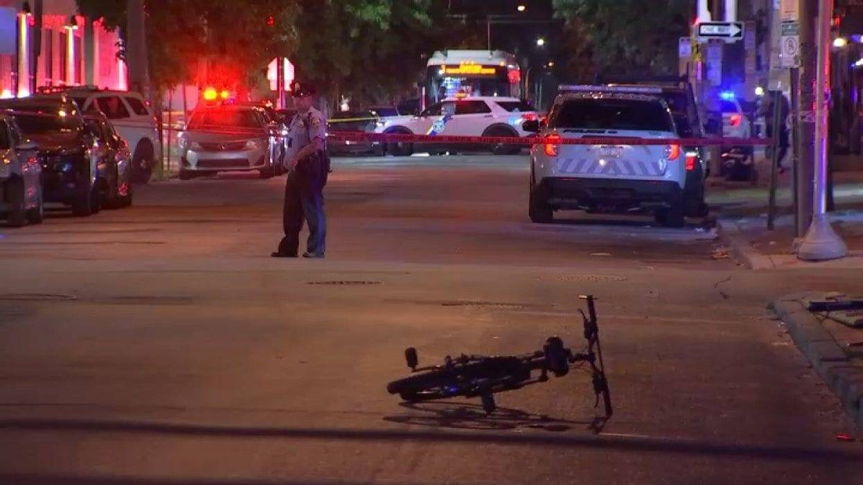 A police officer at the scene of a shooting in North Philadelphia, with the street blocked off. A bicycle is in the street.