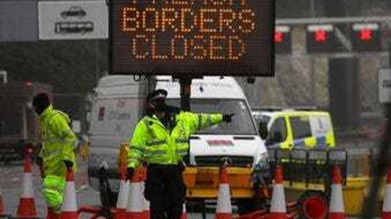 A police officer directs traffic at the entrance to the closed ferry terminal in Dover, England, Monday, Dec. 21, 2020. (AP Photo/Kirsty Wigglesworth)