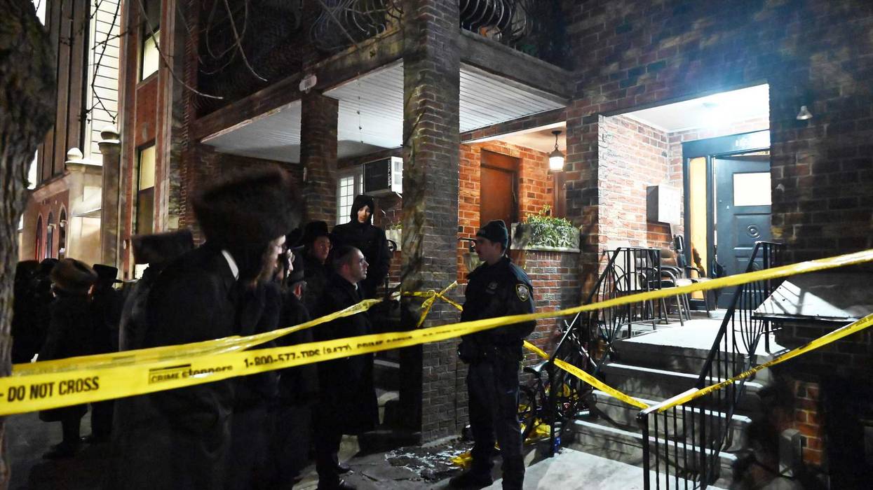 A police officer guards a residential building on 45th Street where a man allegedly stabbed his parents to death on Jan. 20, 2024