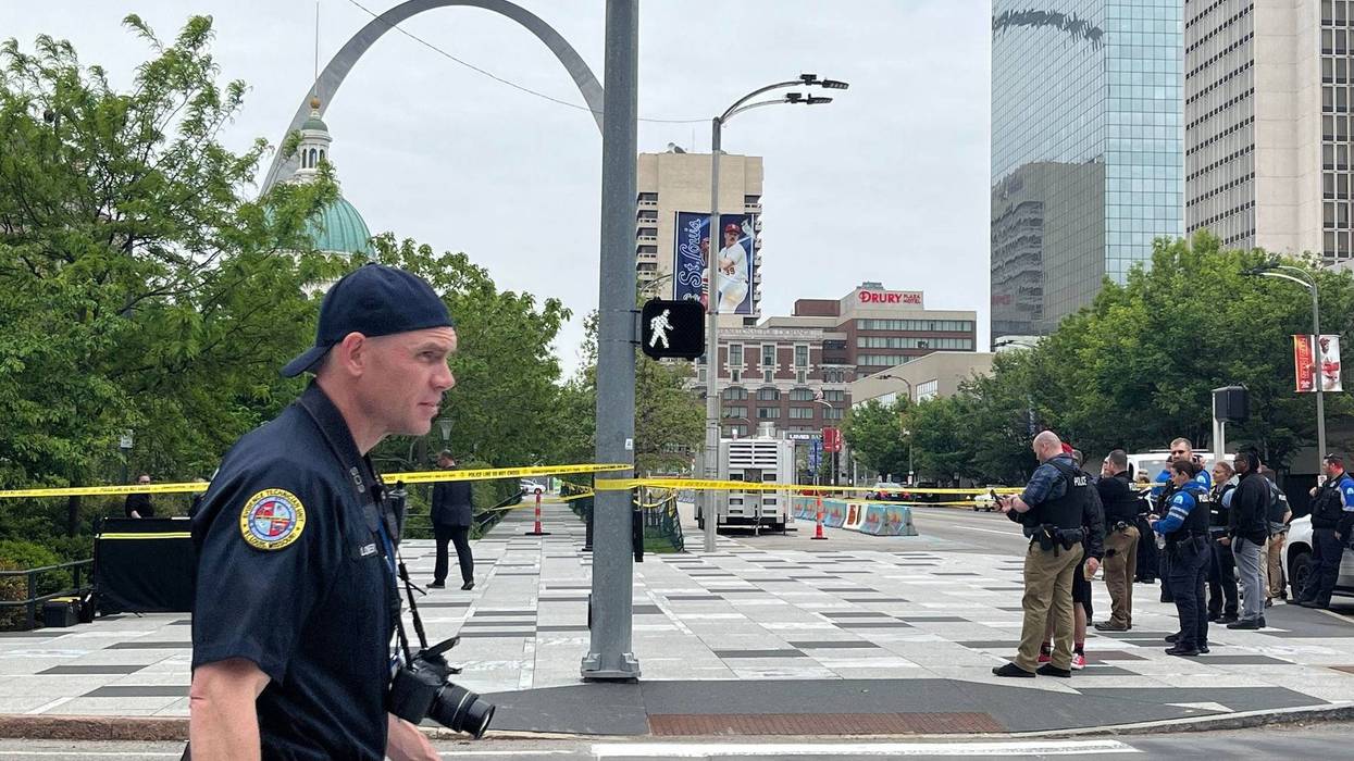 A police photographer walks by the scene where a man was shot and killed downtown on April 27, 2023.