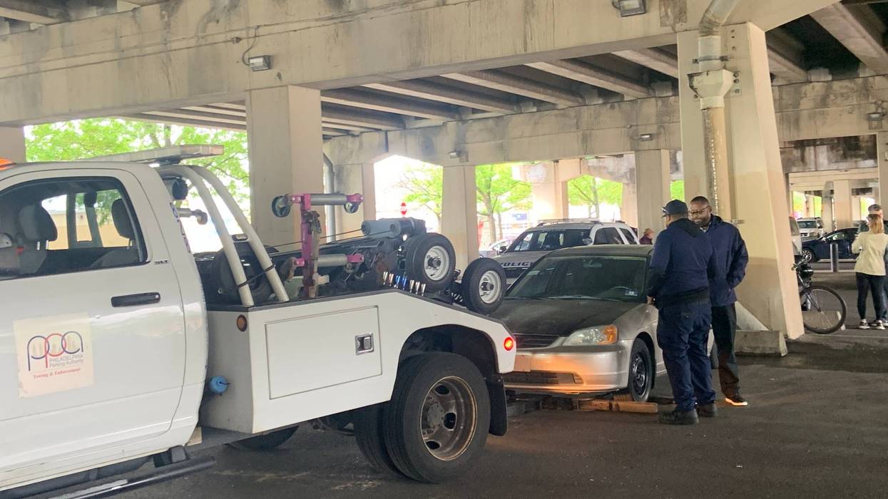 A PPA tow truck tows one of the cars operated on by illegal street mechanics under I-95 in Pennsport.