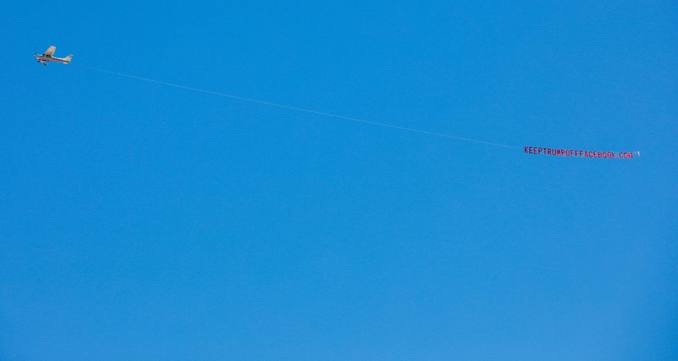 A prop plane flies a banner reading "KEEPTRUMPOFFFACEBOOK.COM" overhead at Facebook