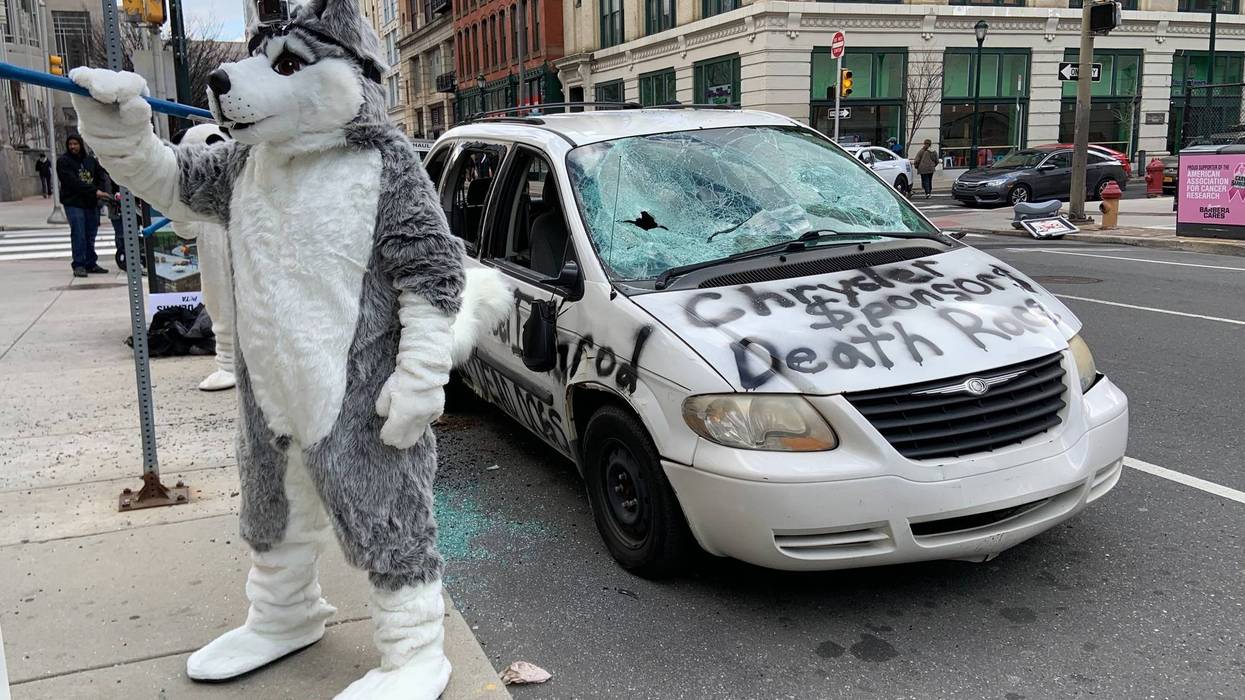A protester dressed in a dog costume helps destroy a Chrysler minivan, as a statement regarding the company's support of the Iditarod sled dog race.