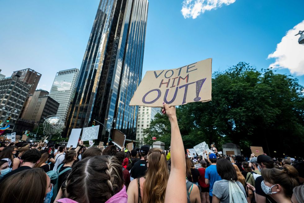 A protester holds a homemade sign above their head that says, "Vote Him Out!" in front of Trump International Hotel and Tower at Columbus Circle on June 14, 2020.