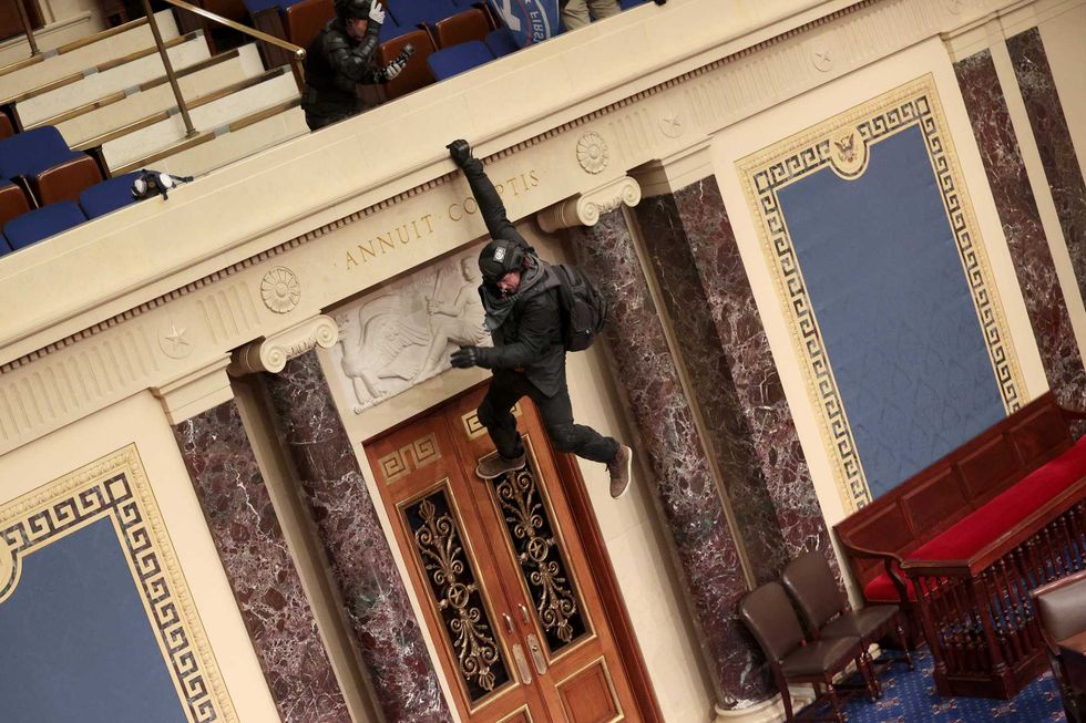 A protester is seen hanging from the balcony in the Senate Chamber on January 06, 2021 in Washington, DC. Congress held a joint session today to ratify President-elect Joe Biden