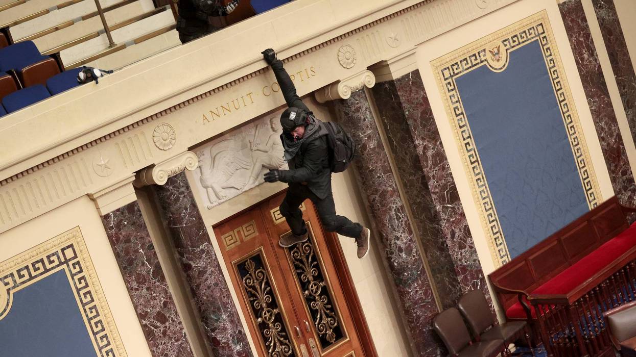 A protester is seen hanging from the balcony in the Senate Chamber on January 06, 2021 in Washington, DC. Congress held a joint session today to ratify President-elect Joe Biden's 306-232 Electoral College win over President Donald Trump. Pro-Trump protesters have entered the U.S. Capitol building after mass demonstrations in the nation's capital.