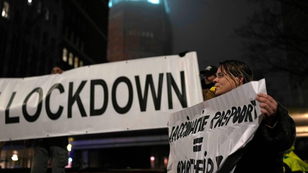 A protestor holds a banner during a small anti-COVID restriction demonstration in the Hague, the Netherlands, Saturday, Dec. 18, 2021.