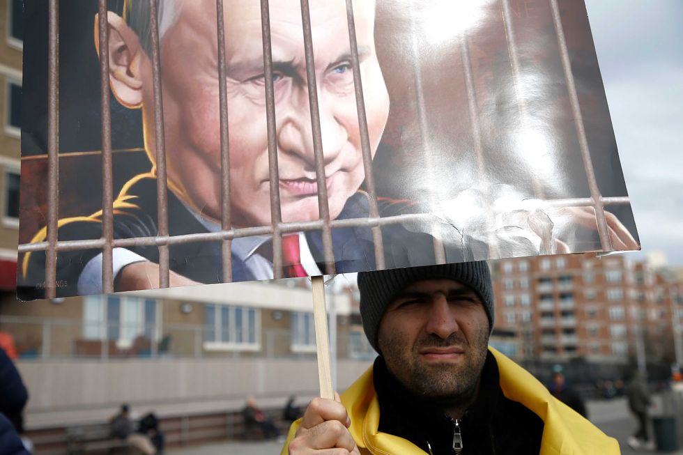 A rally participant holds a caricature of President Putin as others listen to mostly Russian speakers denounce the war in the Ukraine on March 20, 2022 in the Brighton Beach section of the Brooklyn borough of New York City.