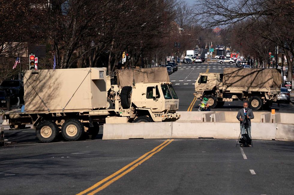 A reporter does a television hit in front of military vehicles near the U.S. Capitol on January 14, 2021 in Washington, DC. Security has been increased throughout Washington following the breach of the U.S. Capitol last Wednesday, and leading up to the Presidential Inauguration.