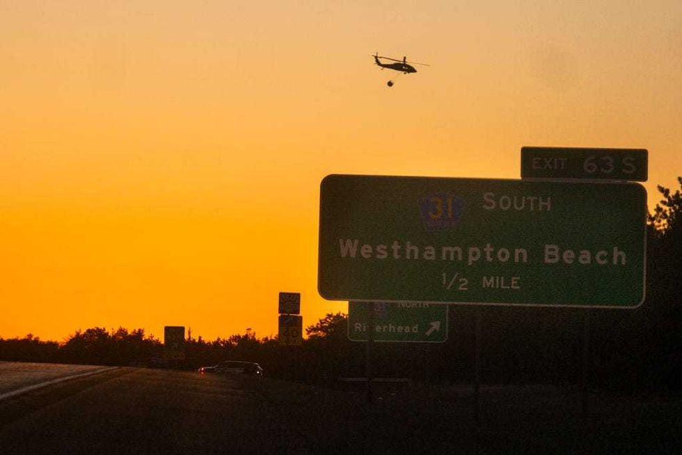 A rescue helicopter carries water along Route 27 on March 8, 2025 in Westhampton, New York.
