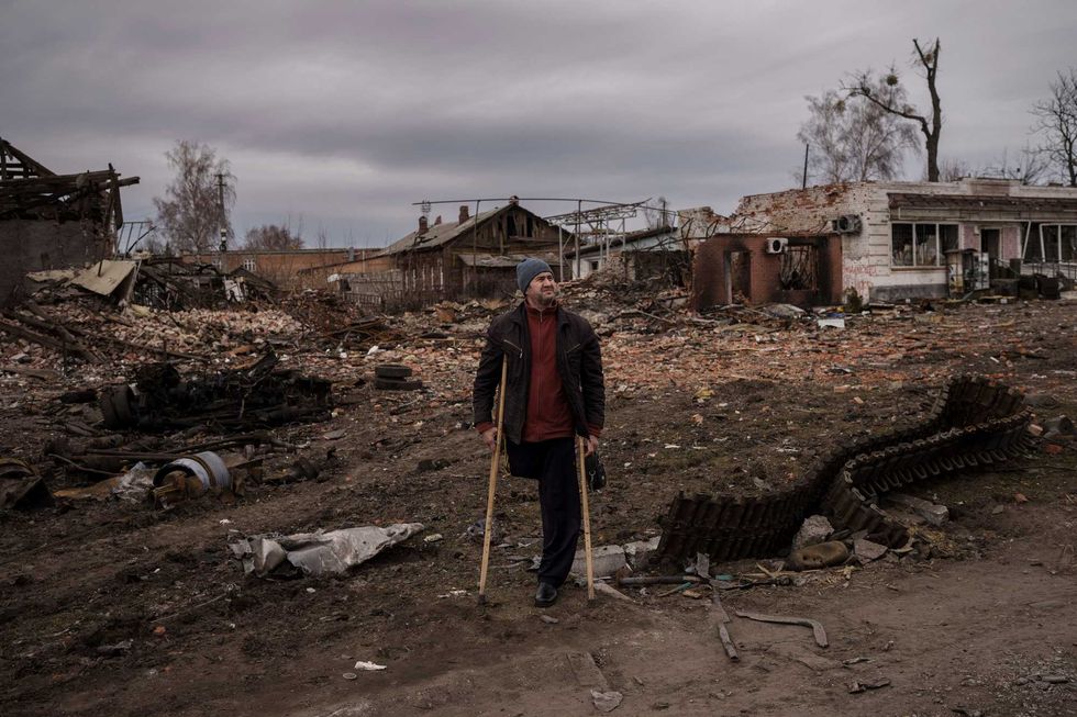 A resident stands next to parts of a destroyed Russian tank in the town of Trostsyanets, Ukraine, Monday, March 28, 2022