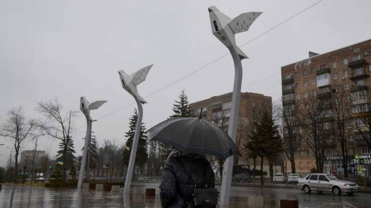 A resident walks with an umbrella under the rain on Freedom Square on February 18, 2022 in Mariupol, Ukraine.