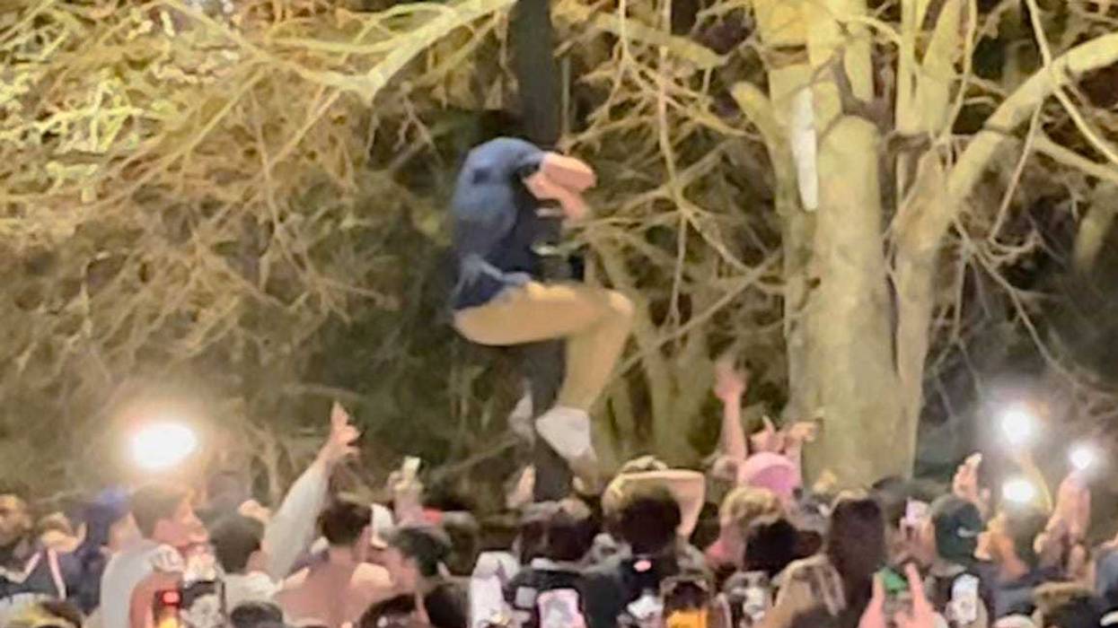 A rioter at UConn climbs a metal light post, trying to take it down, as others look on, after the Huskies won the men's basketball national championship, 4/3/23