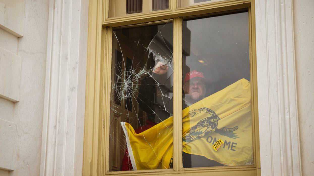 A rioter gestures from inside a broken Capitol window during insurrection by Trump supporters, Jan. 7, 2021.