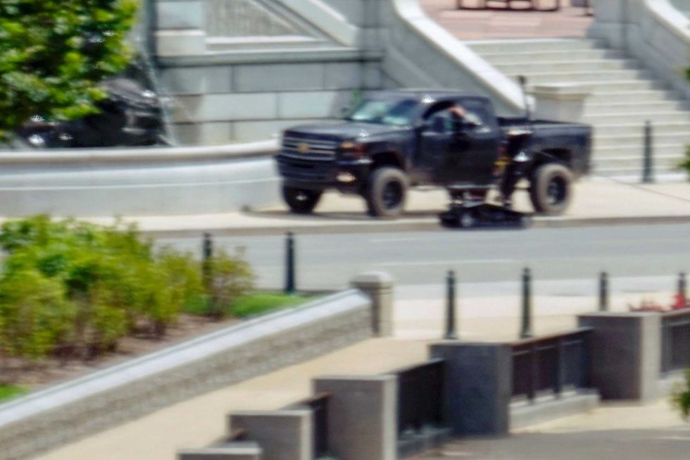 A robot is seen near a person in a pickup truck parked on the sidewalk in front of the Library of Congress