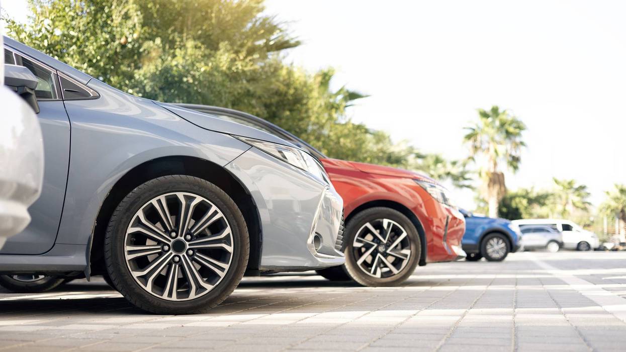 A row of new colorful vehicles on the parking. A line of used cars and trucks for sale