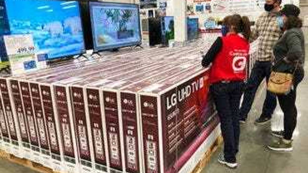 A sales associate helps customers as they consider the purchase of a big-screen television at a Costco warehouse on Wednesday, Nov. 18, 2020, in Sheridan, Colo. (AP Photo/David Zalubowski)