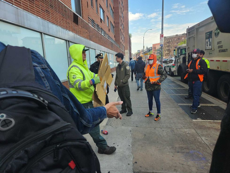 A sanitation worker walks away with two pieces of cardboard. Vails made clear to the sweep team that she would return as soon as they left, so this is seemingly the only change to the area achieved by the sweep.