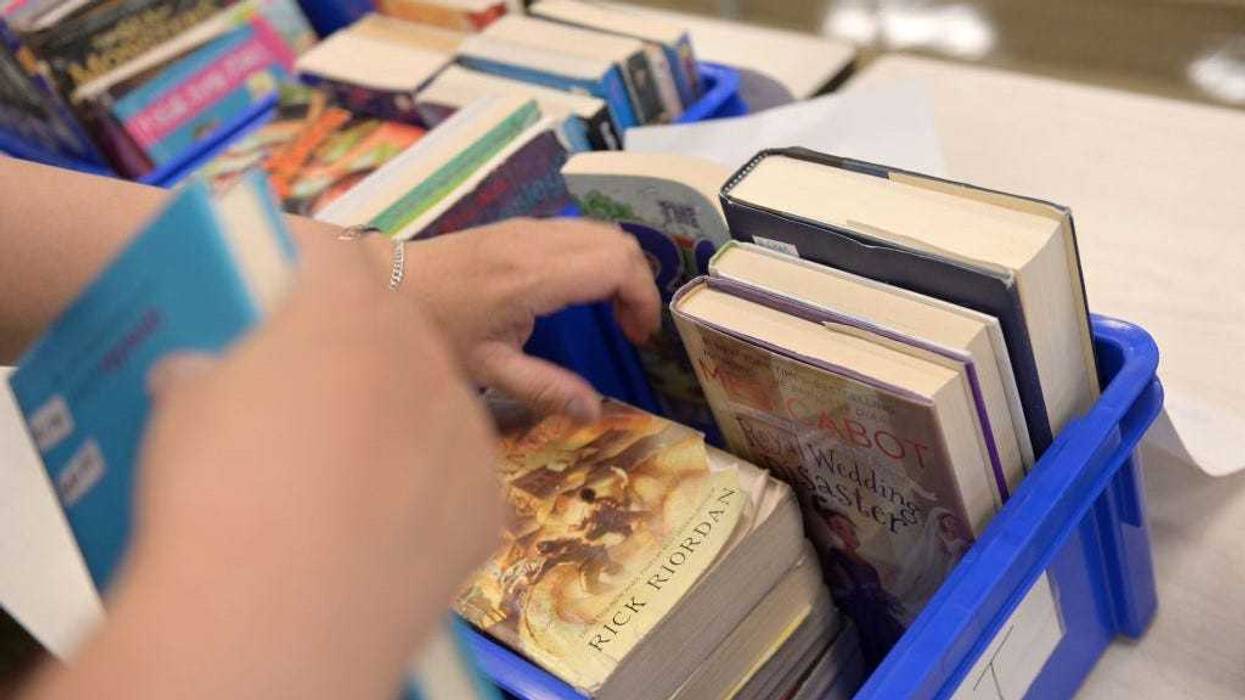 A schoolteacher collects library books from students who just graduated and but borrowed them before schools were shut down at Yung Wing School P.S. 124 on June 29, 2020 in New York City.
