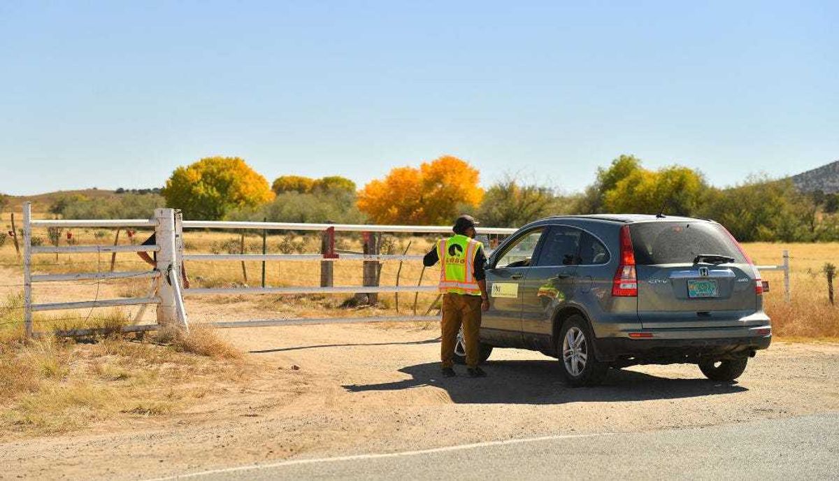 A security guard speaks to a person from the Office of the Medical Investigator at the entrance to the Bonanza Creek Ranch on October 22, 2021, in Santa Fe, New Mexico.