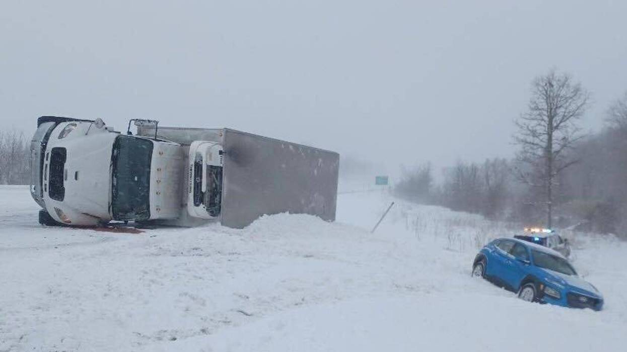 A semi lies on its side on a snow-covered stretch of northbound US-131. Another vehicle and a sheriff's patrol car are in the ditch on the side of the highway.