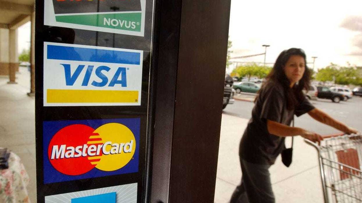 A shopper passes a shop door advertising acceptance of purchases with Master Card, Visa, and other credit cards April 29, 2003 in Bakersfield, California.