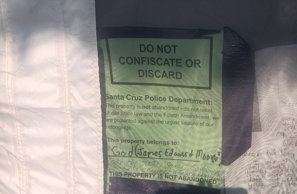 A sign is posted on a tent near the intersection of Highway 1 and Highway 9 in Santa Cruz.