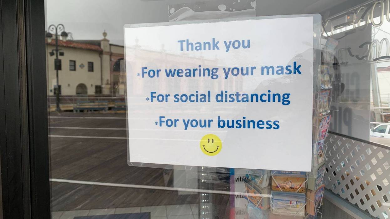 A sign on a business door reminding people to wear masks