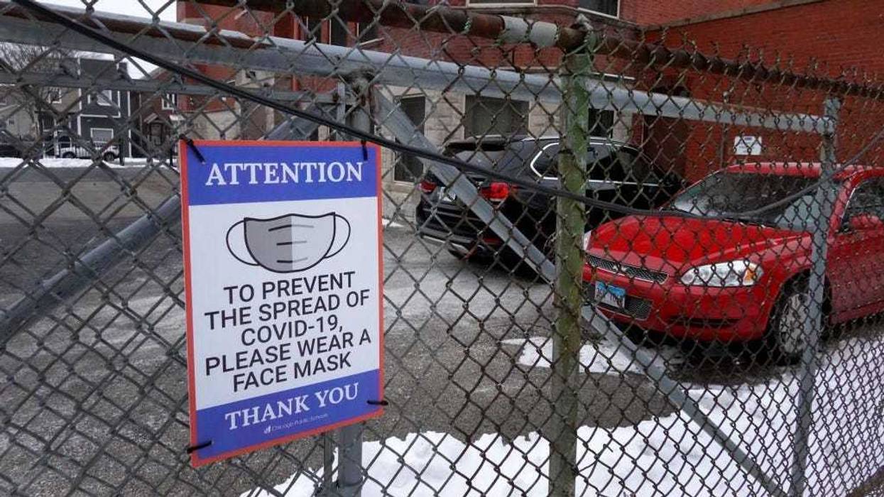 A sign on the fence outside of Lowell elementary school asks students, staff and visitors to wear a mask to prevent the spread of COVID-19 on January 05, 2022 in Chicago, Illinois.