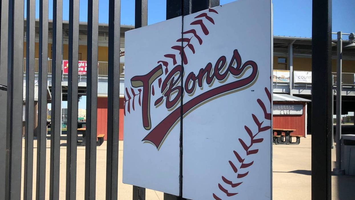 A sign reading "T-Bones" hangs on the gate of the baseball stadium